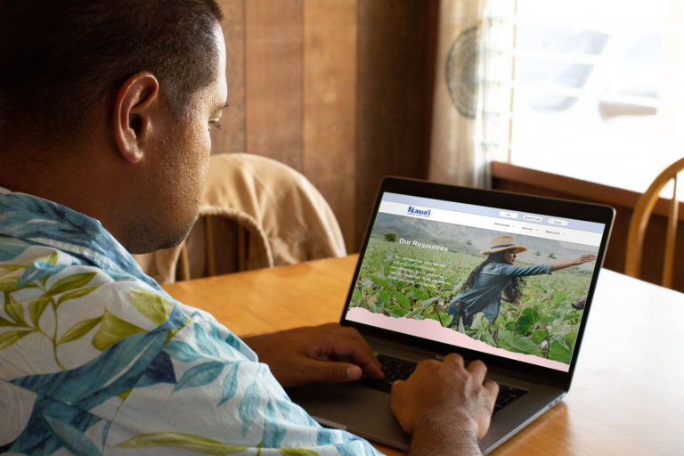 Man explores the resources available on the Kauai FCU website on a laptop